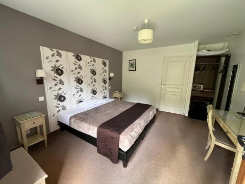 a bedroom with a bed and a table and a door at Logis Hotel-Restaurant "Auberge Le Petit pont" in Tennie