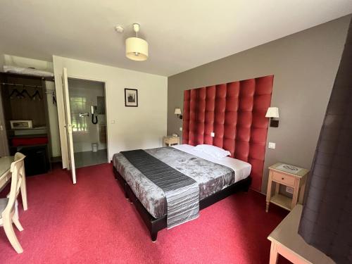 a bedroom with a large bed with a red headboard at Logis Hotel-Restaurant "Auberge Le Petit pont" in Tennie