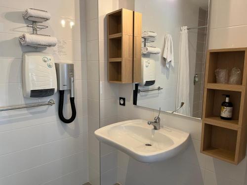 a white bathroom with a sink and a phone at Logis Hotel-Restaurant "Auberge Le Petit pont" in Tennie