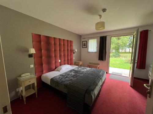a bedroom with a large bed with a red padded headboard at Logis Hotel-Restaurant "Auberge Le Petit pont" in Tennie