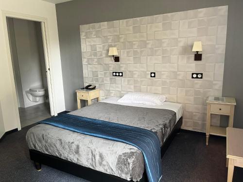 a bedroom with a bed and two tables and a toilet at Logis Hotel-Restaurant "Auberge Le Petit pont" in Tennie