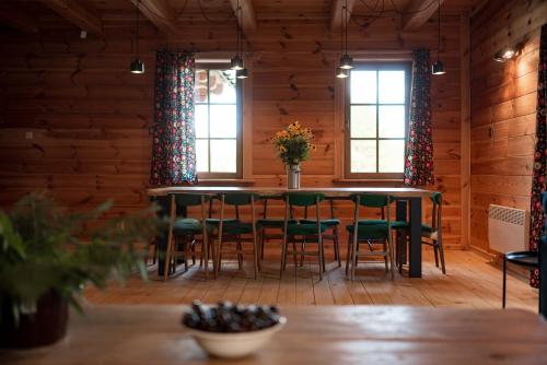 a dining room with a table and chairs and windows at Osada Dębno 