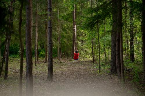 a woman in a red dress walking through a forest at Osada Dębno 