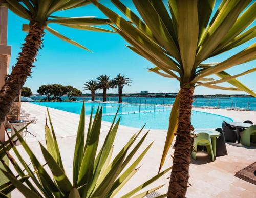 a view of a swimming pool with two palm trees at Sunny Ofir in Fão