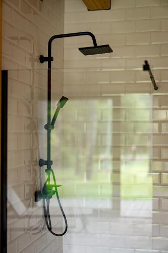 a shower with a green shower head in a bathroom at Osada Dębno 