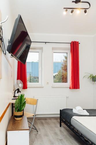 a bedroom with a bed and a desk and a television at Arcus Premium Hostel in Warsaw