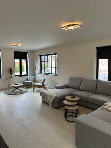 a living room with a couch and tables and windows at Sœur in Berlare