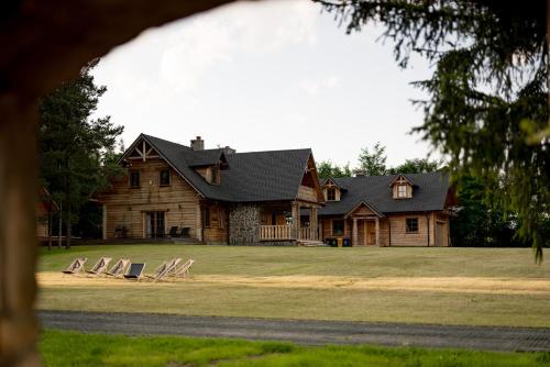 a large wooden house with chairs on the lawn at Osada Dębno 