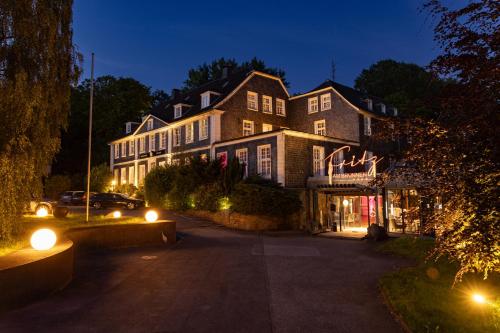 a large house with lights on a street at night at Parkhotel FRITZ am Brunnen in Schwelm