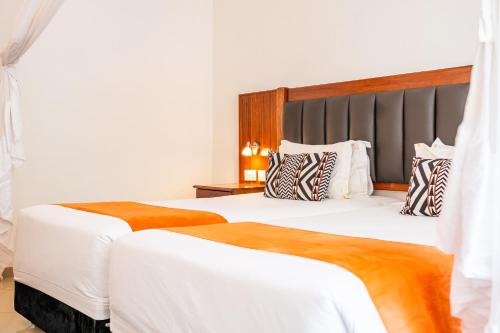 two beds in a hotel room with white walls at Victoria Falls Rainbow Hotel in Victoria Falls