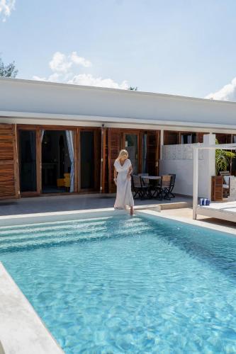 a woman is standing next to a swimming pool at ZAN Orient Beach Hotel in Bwejuu