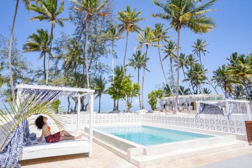 a woman sitting in a hammock next to a pool at ZAN Orient Beach Hotel in Bwejuu