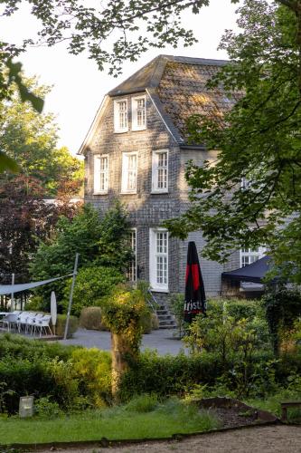 a house with a table and an umbrella in front of it at Parkhotel FRITZ am Brunnen in Schwelm