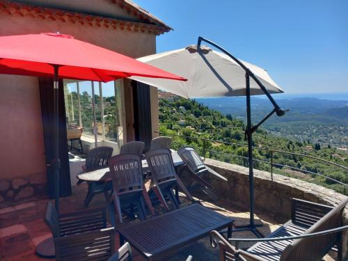a patio with a table and chairs and an umbrella at La villa Haute in Cabris