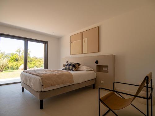 a bedroom with a bed and a large window at Villa Adeona in Zonza