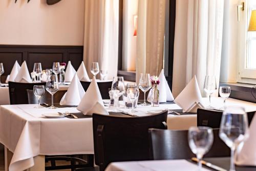 a restaurant with white tables and chairs with wine glasses at Parkhotel FRITZ am Brunnen in Schwelm