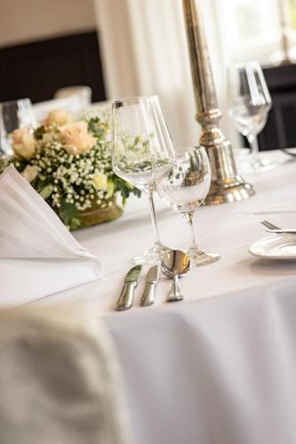 a table with wine glasses and a vase of flowers at Parkhotel FRITZ am Brunnen in Schwelm