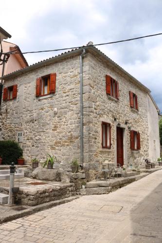 an old stone building with red shuttered windows at Rooms Poli Luce - Room Franica in Gračišće