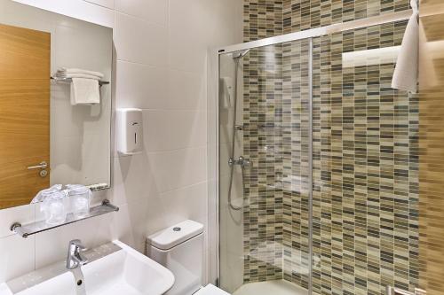 a bathroom with a shower and a toilet and a sink at The Book Factory Hostel by gaiarooms in Valladolid