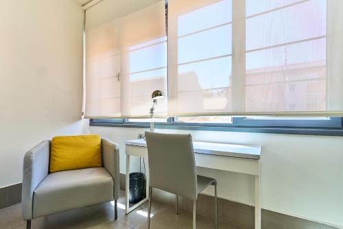 a desk and two chairs in a room with a window at The Book Factory Hostel by gaiarooms in Valladolid