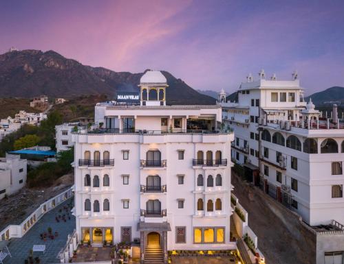 a view of a white building with mountains in the background at Maan Vilas - A Boutique Hotel Udaipur in Udaipur