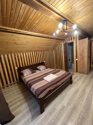 Un dormitorio con una cama en una habitación de madera. en Oniks, en Mykulychyn
