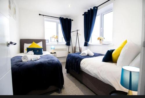 a bedroom with two beds with blue and yellow pillows at Spacious contactor family Apartment in Swindon