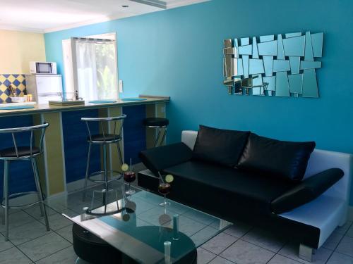 a living room with a black couch and a blue wall at Location dans les Landes et le Pays basque in Labenne
