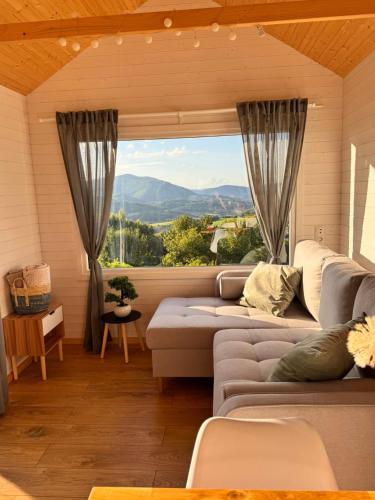 a living room with a couch and a large window at Horyzont Spokoju in Podobin