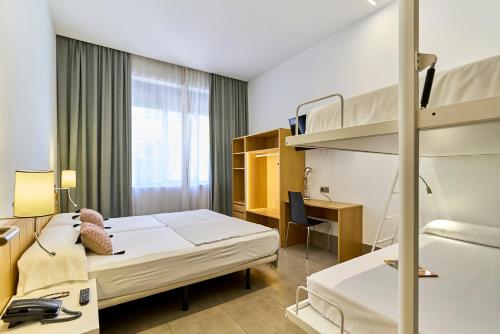a hotel room with two beds and a desk at The Book Factory Hostel by gaiarooms in Valladolid