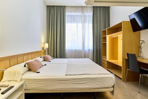a bedroom with a bed and a desk and a television at The Book Factory Hostel by gaiarooms in Valladolid