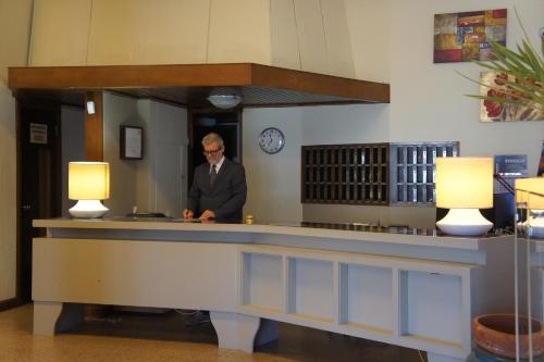 un homme debout derrière un comptoir de réception dans une pièce dans l'établissement Hotel Al Sant'Andrea, à Sarzana