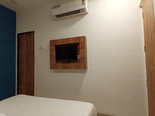 Un dormitorio con una cama y un televisor en una pared. en Hotel West Side Stay, en Bombay