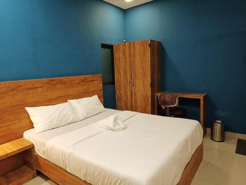 Un dormitorio con una cama blanca con una pared azul. en Hotel West Side Stay, en Bombay