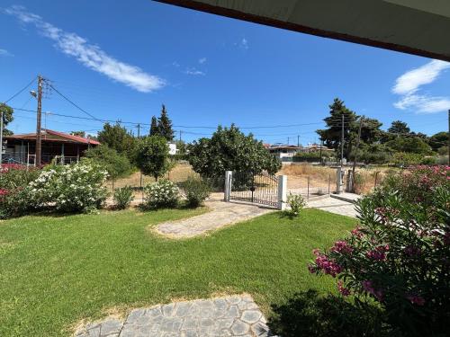 a yard with a fence and grass and flowers at Modern Summer House Popi in Pálioura
