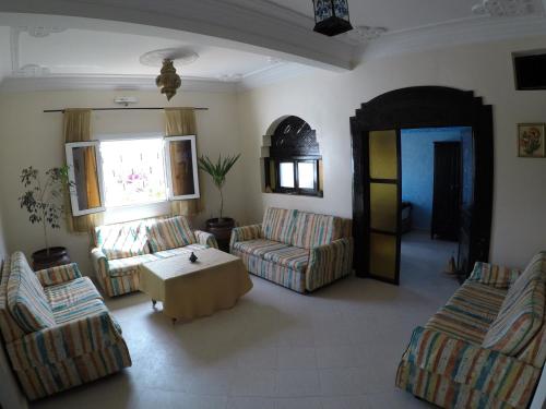 a living room with couches and a table and a window at Original Surf Morocco in Tamraght Ouzdar