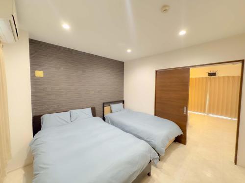 two beds sitting next to each other in a bedroom at 恩納村仲泊海の見える2LDkアパート in Onna