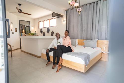 two people sitting on a bed in a room at ZAN Tropical Island in Bwejuu