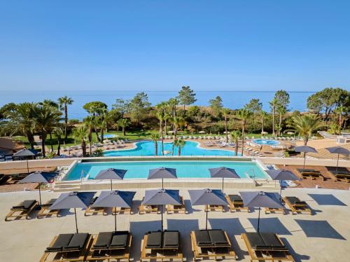 a swimming pool with chairs and umbrellas at PortoBay Blue Ocean in Albufeira