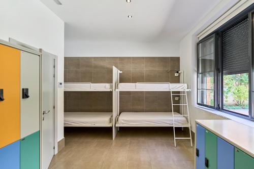 a room with two bunk beds and a window at The Book Factory Hostel by gaiarooms in Valladolid