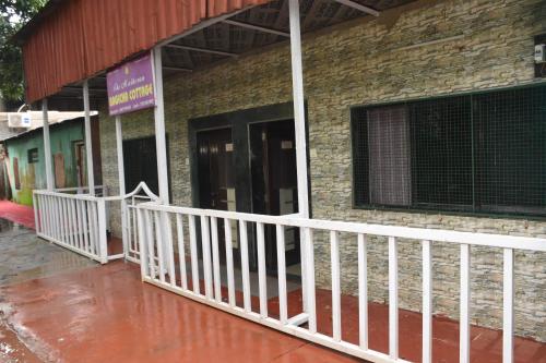 a brick building with a white railing on a porch at The Grand Bagicha Residency Matheran in Matheran