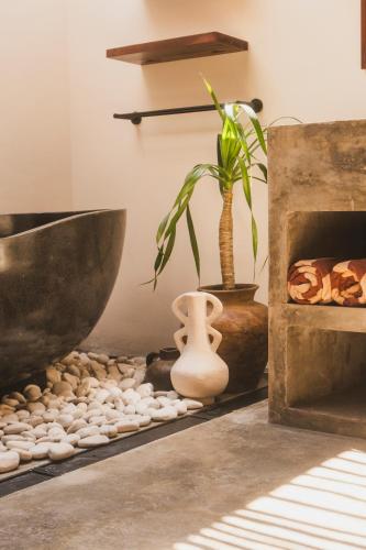 a room with a bowl and a plant and a tub at Savanna Ubud in Ubud