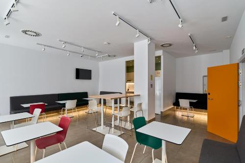 a dining room with white tables and colorful chairs at The Book Factory Hostel by gaiarooms in Valladolid