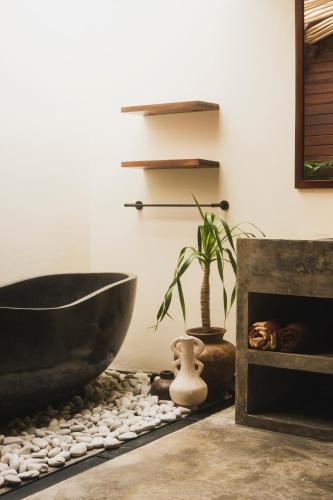 a bathroom with a bath tub and a plant at Savanna Ubud in Ubud