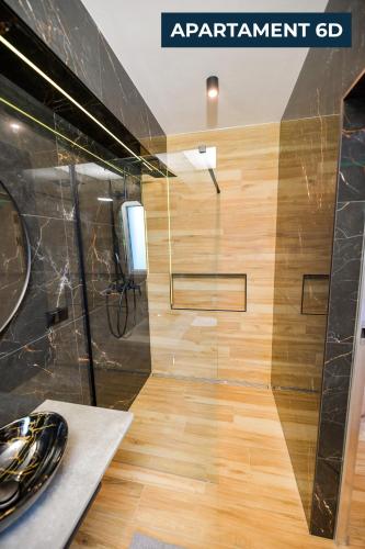 a bathroom with a shower with a wooden floor at Słoneczne Wzgórze Zator in Zator