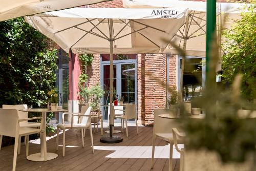 a patio with tables and chairs and an umbrella at The Book Factory Hostel by gaiarooms in Valladolid