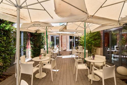 a restaurant with white tables and chairs and umbrellas at The Book Factory Hostel by gaiarooms in Valladolid