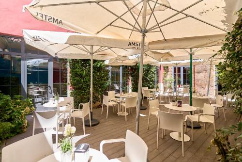 a restaurant with white tables and chairs and umbrellas at The Book Factory Hostel by gaiarooms in Valladolid