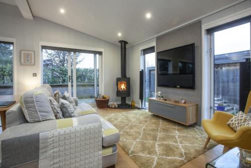 a living room with a couch and a flat screen tv at Nyland Lodge - Hot Tub - Fireplace - Free Parking & WiFi in Cheddar