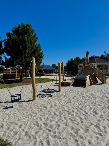 a playground with swings and a slide in the sand at EMSLAND-CAMP in Haar